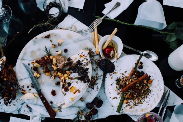 An overhead view of plates holding the remains of finished dishes after a shared meal.