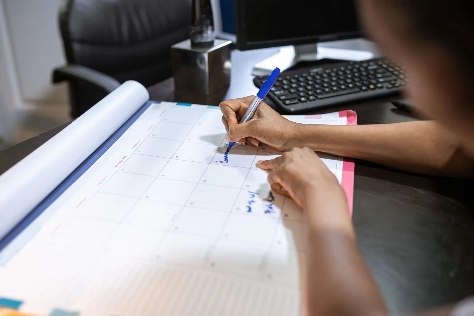A woman marking dates on a desk calendar.