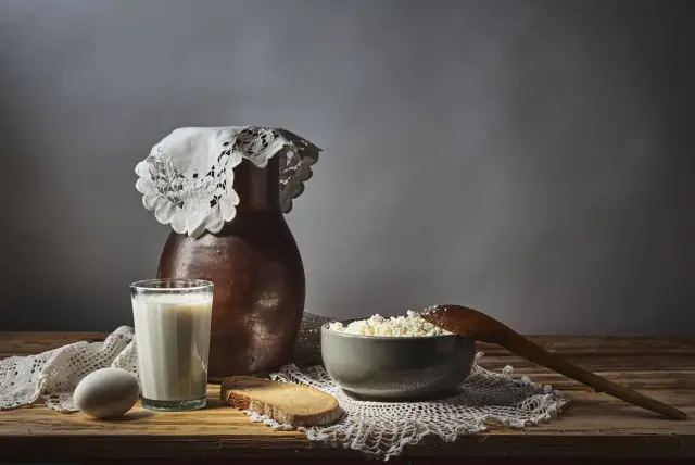 A rustic still life of milk, cottage cheese and bread on a wooden table.