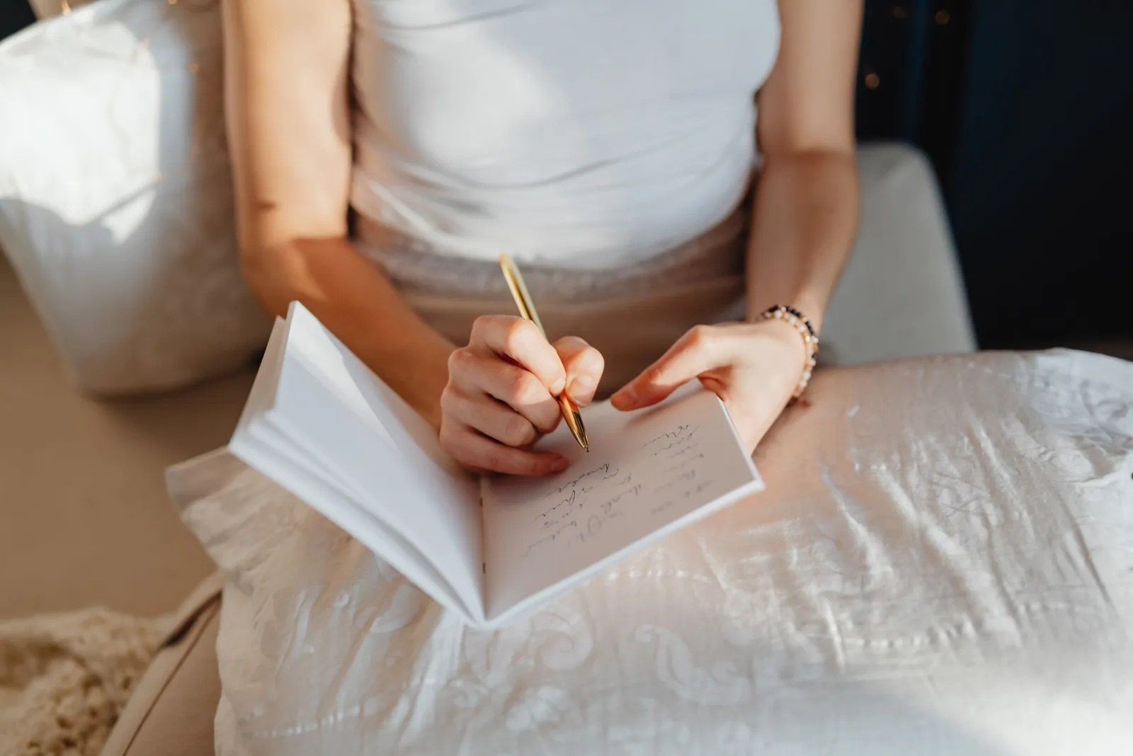 A woman writing in a journal while sitting comfortably indoors.