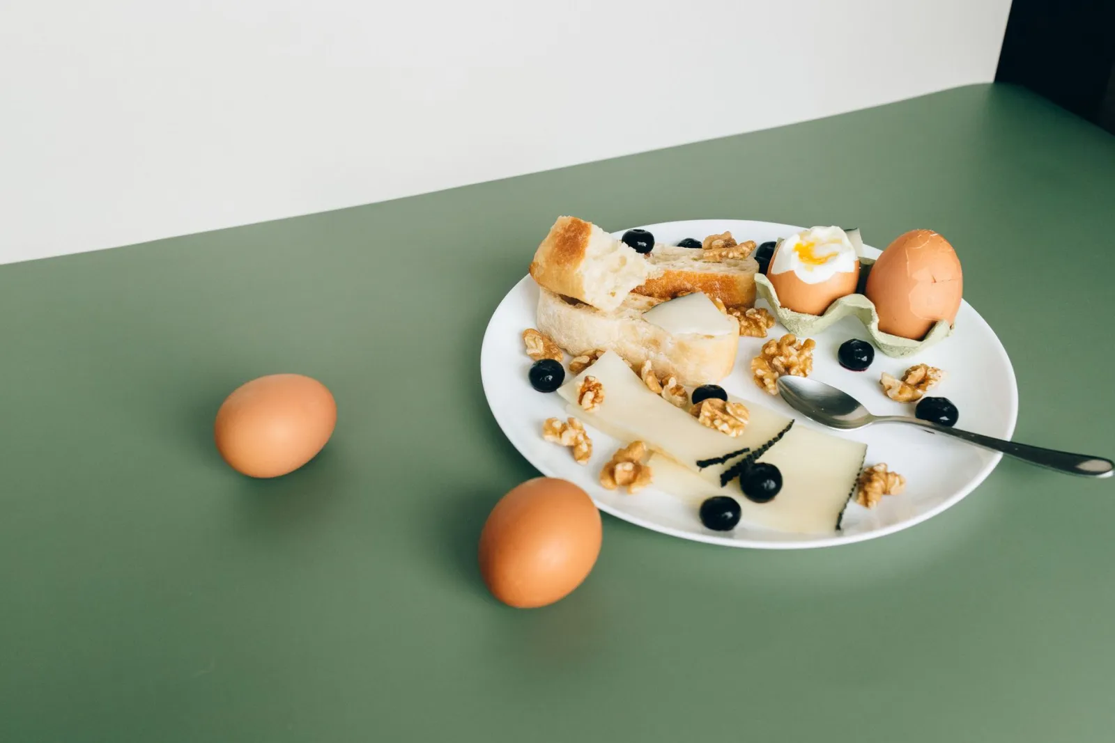 A plate of cheese, boiled eggs, walnuts, and blueberries.