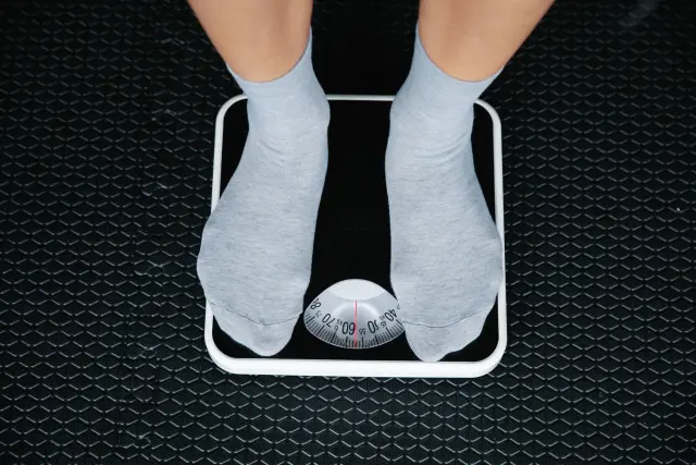 A pair of bare feet stepping onto a bathroom scale in soft morning light.