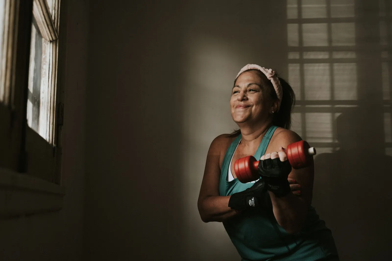 A confident woman lifting dumbbells during a home strength session.