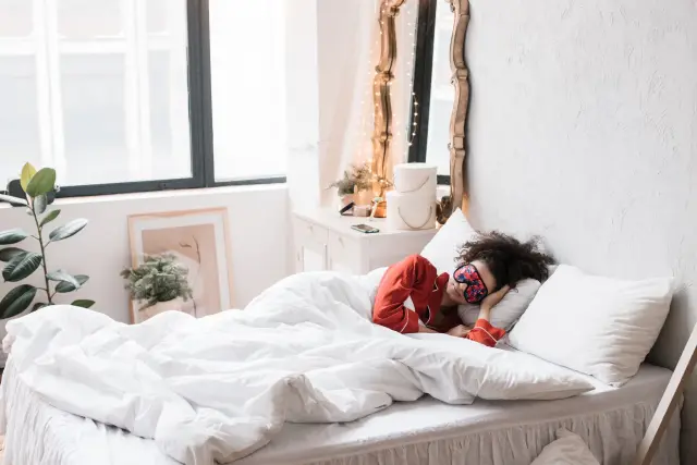 A person asleep in a dim bedroom at night.