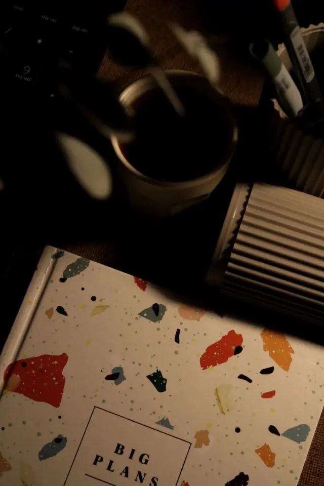 An open notebook beside a coffee mug on a home desk in warm morning light.