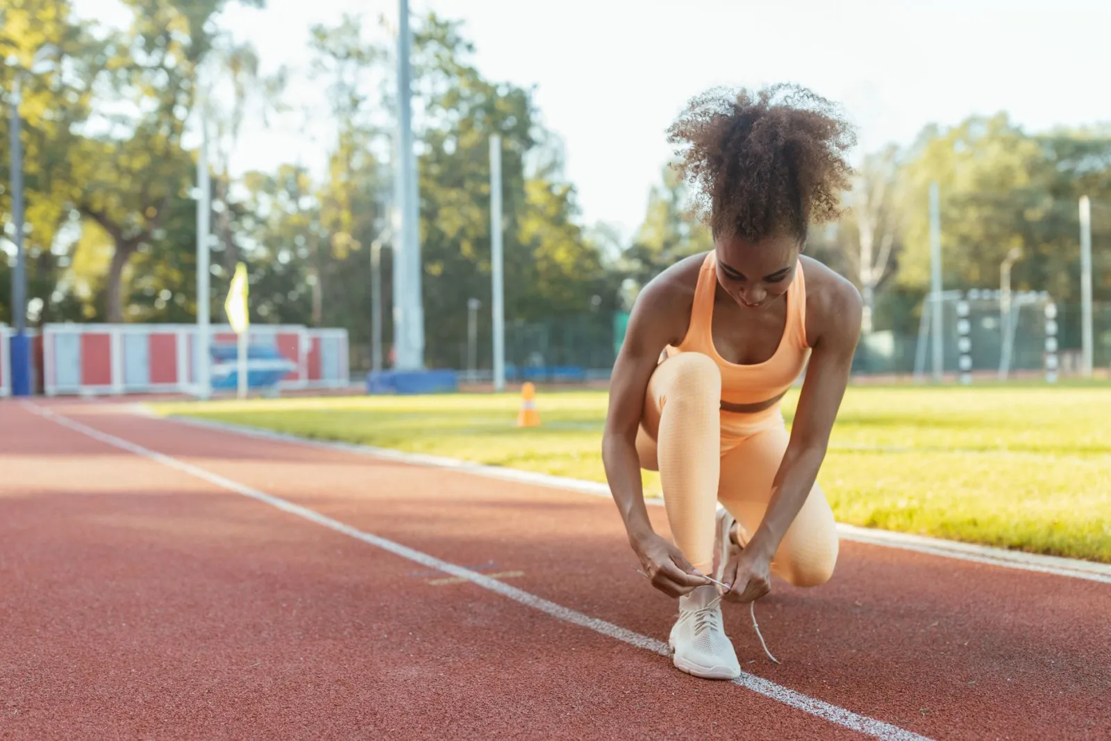 A woman tying her running shoes outdoors.