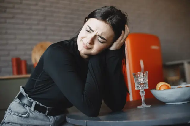 A person sitting quietly at a table with an untouched plate in front of them.
