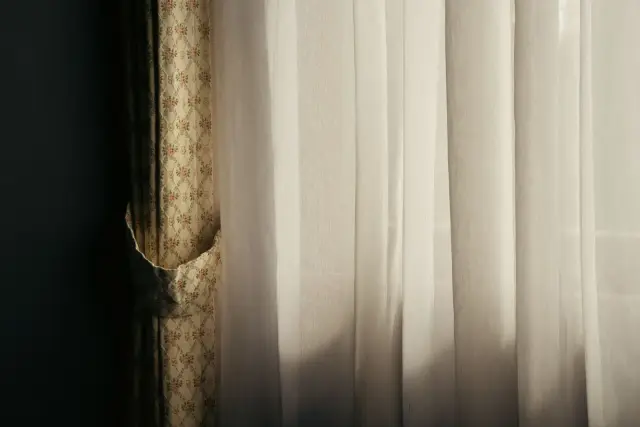 Soft daylight coming through a sheer white curtain in a quiet room.