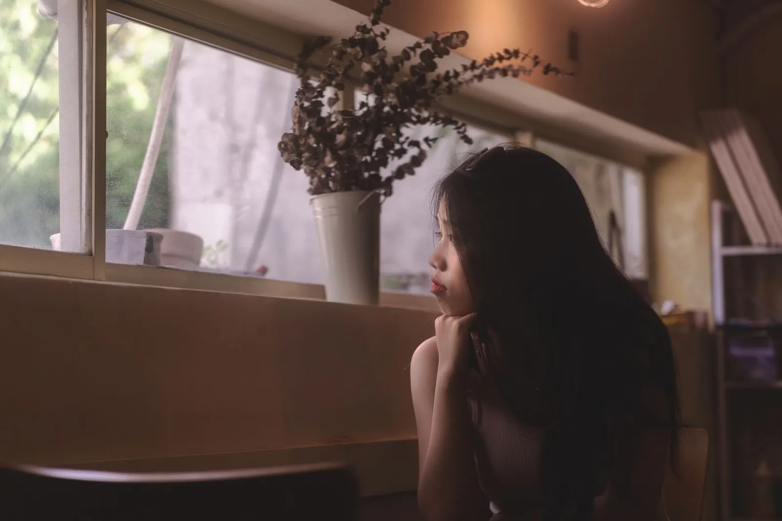 A woman gazing thoughtfully out of a window.