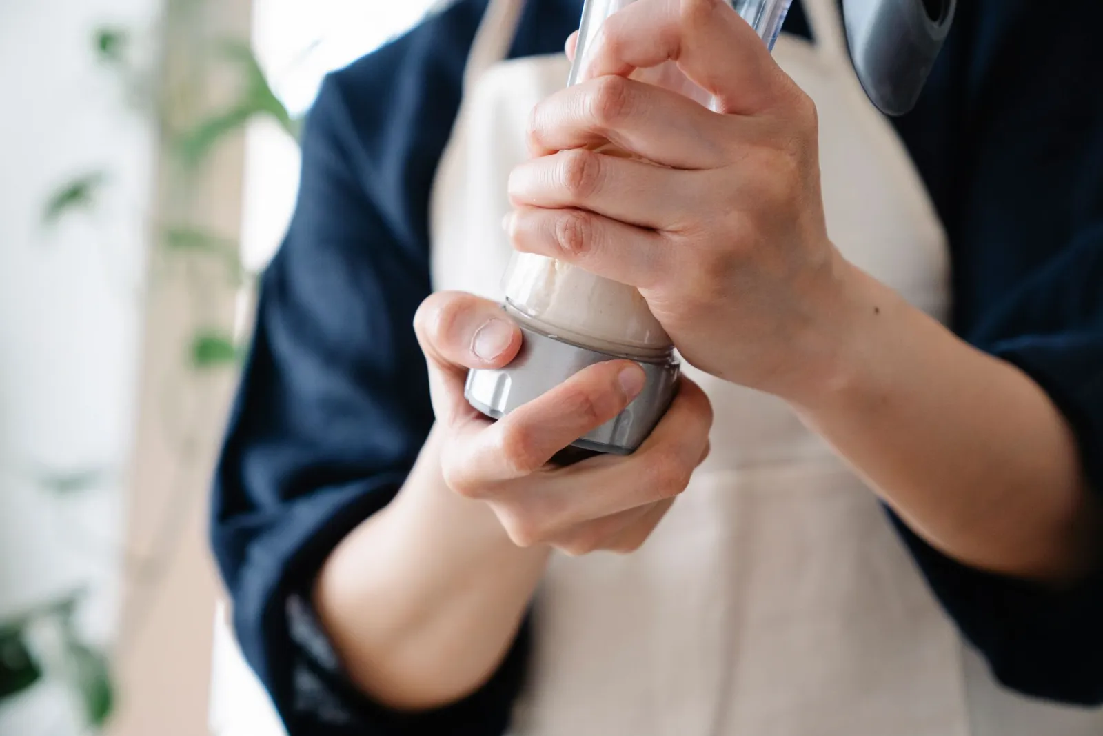 A person shaking a protein shake in a kitchen.