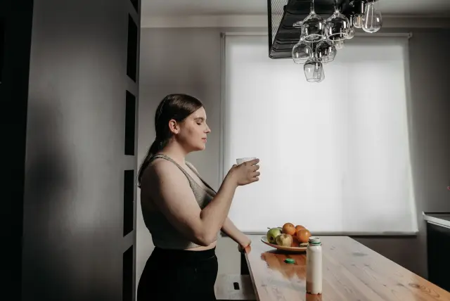 A woman with eyes closed savors a smoothie, embracing a healthy lifestyle in the kitchen.