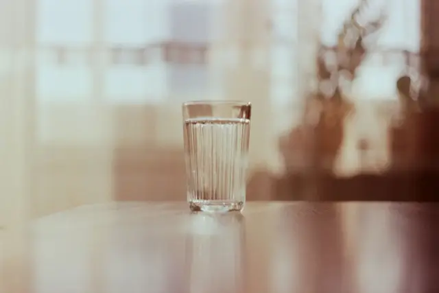 A clear glass of water on a table in soft window light.