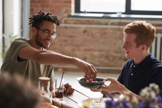 Two friends sharing a relaxed meal at an indoor dining table.