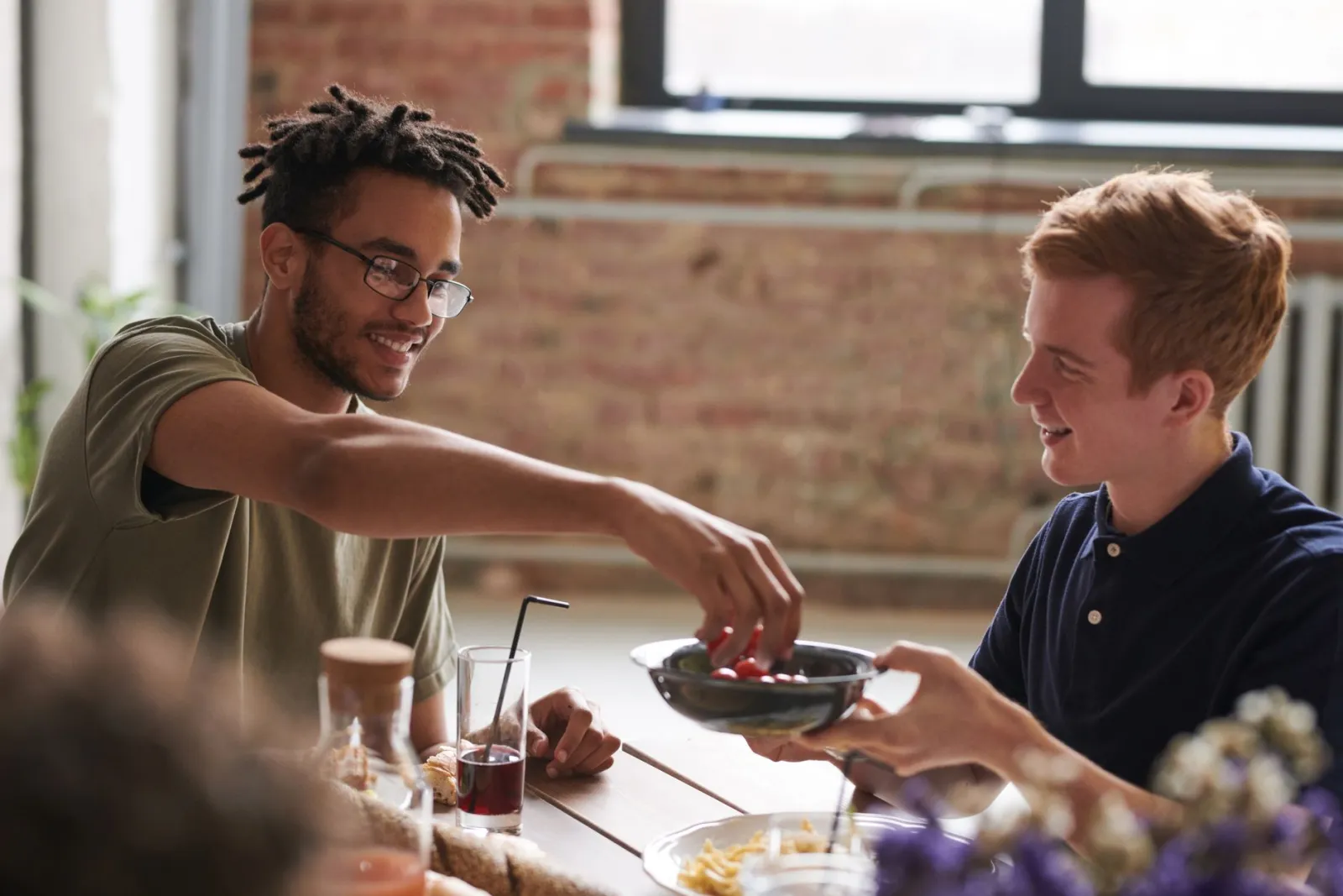 Two friends sharing a relaxed meal at an indoor dining table.