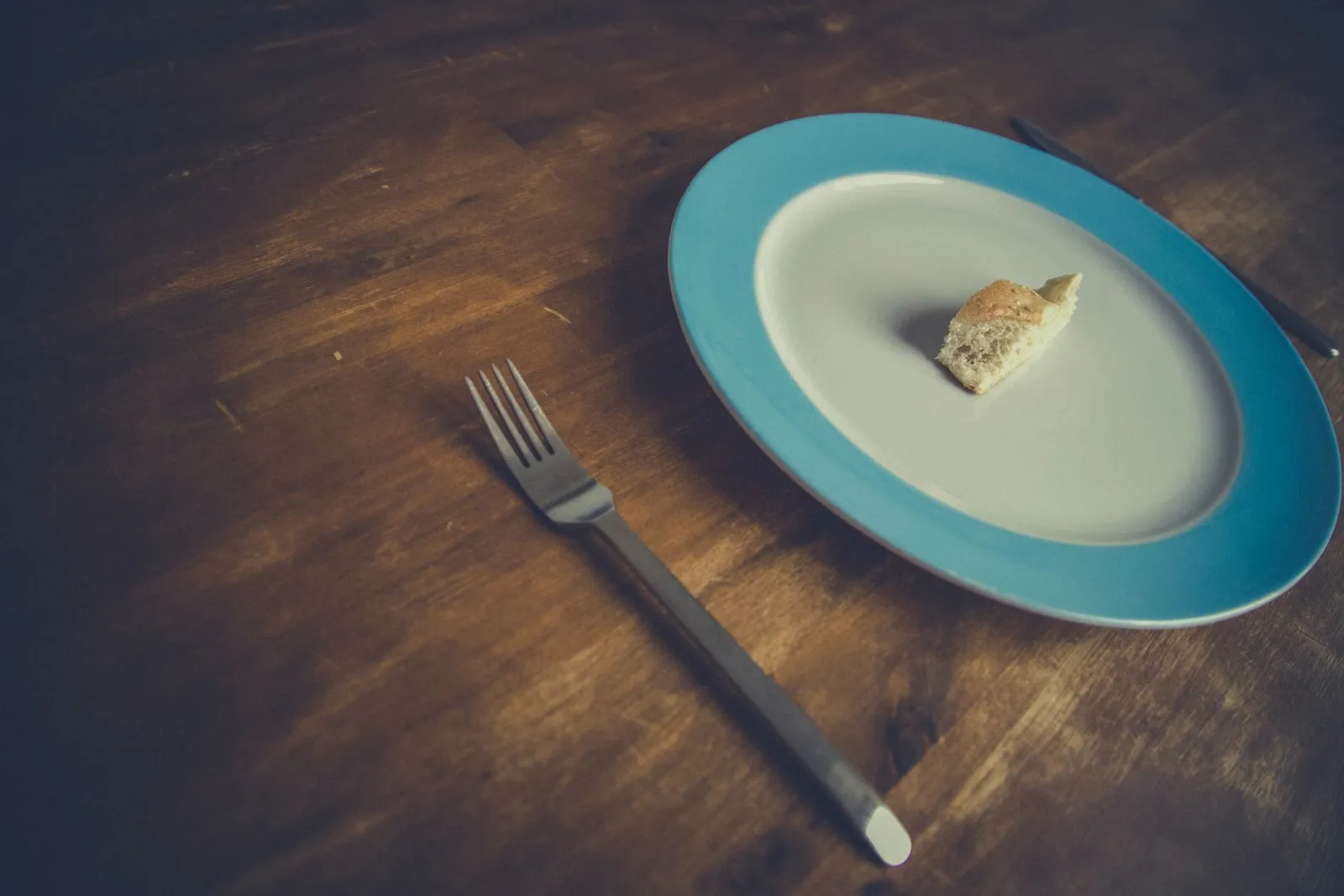A small, minimalist portion of food on a plate with a fork and knife resting beside it.