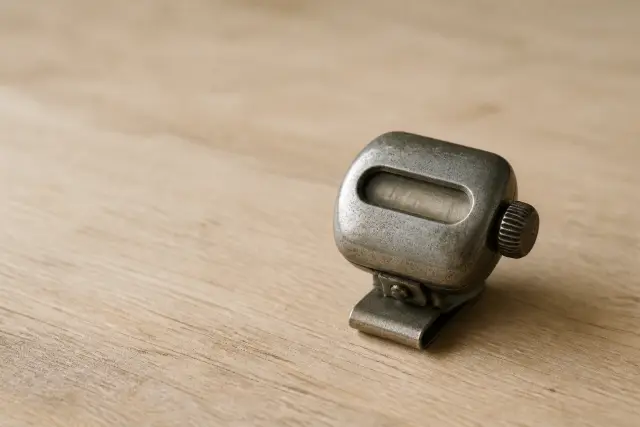 A vintage mechanical step counter resting on a wooden surface in soft daylight.