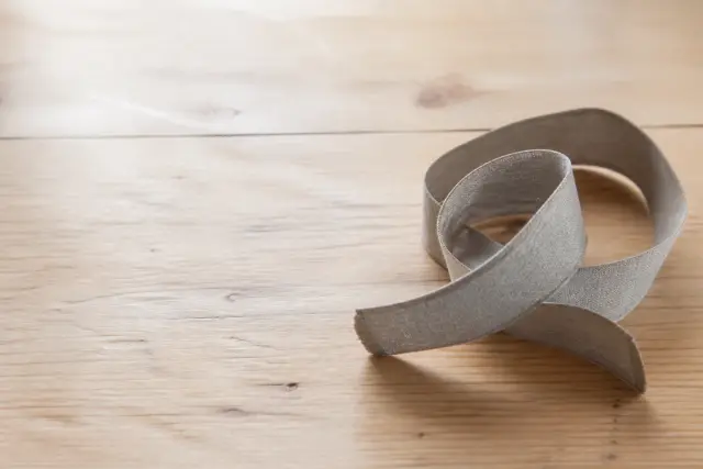 A cloth tape measure resting on a plain wooden surface in soft daylight.